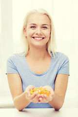 Image showing happy woman holding fish oil capsules at home