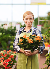 Image showing happy woman holding flowers in greenhouse