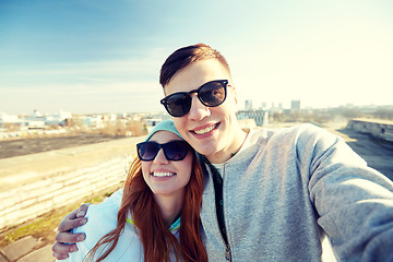 Image showing happy teenage couple taking selfie on city street