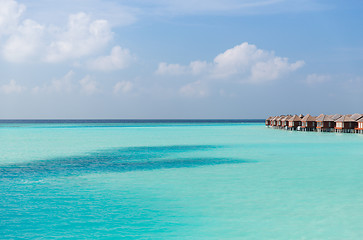 Image showing bungalow huts in sea water on exotic resort beach