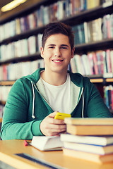 Image showing male student with smartphone and books in library