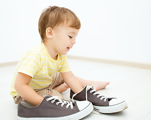 Image showing Boy is playing with big sneakers