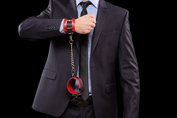 Image showing man in a business suit with leather bound. handcuffs. sex Toys