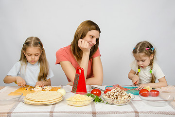 Image showing Mother with tenderness looks like her little daughter to help her in the kitchen to prepare meals