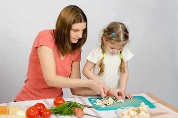 Image showing Mom shows daughter how to cut a small knife mushrooms