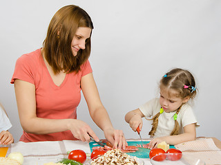 Image showing Mom teaches daughter to a six-year cut with a knife products for cooking at the kitchen table