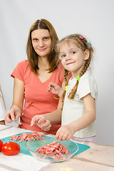 Image showing Little six year old girl helps mother to cook at the kitchen table