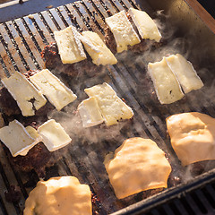 Image showing Beef burgers being grilled on barbecue.