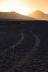 Image showing Wheel tracks in sand and dramatic landscape.