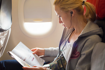 Image showing Woman reading magazine on airplane.