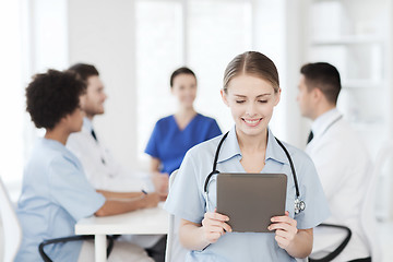 Image showing happy doctor with tablet pc over team at clinic