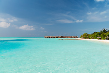 Image showing bungalow huts in sea water on exotic resort beach