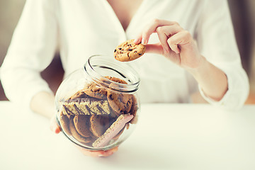 Image showing close up of hands with chocolate cookies in jar