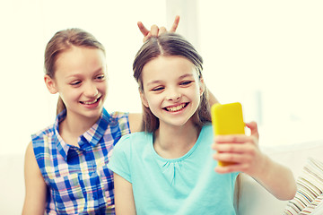 Image showing happy girls with smartphone taking selfie at home