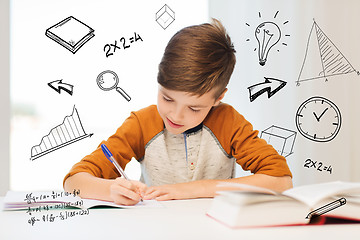 Image showing smiling student boy writing to notebook at home