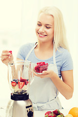 Image showing smiling woman with blender preparing shake at home