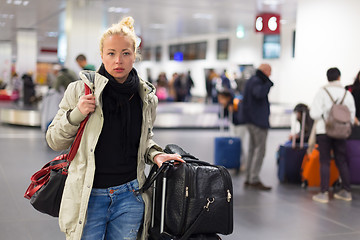 Image showing Female traveler transporting luggage in airport.