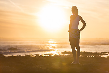 Image showing Woman on sandy beach watching sunset.