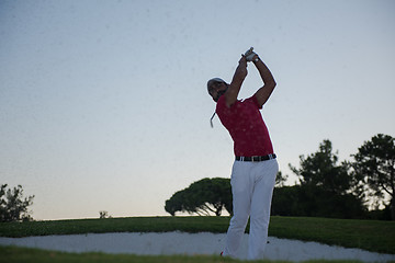 Image showing golfer hitting a sand bunker shot on sunset