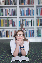 Image showing female student study in library, using tablet and searching for 