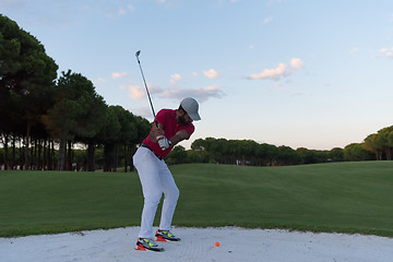 Image showing golfer hitting a sand bunker shot on sunset