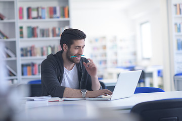 Image showing student in school library using laptop for research