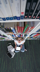 Image showing female student study in library, using tablet and searching for 