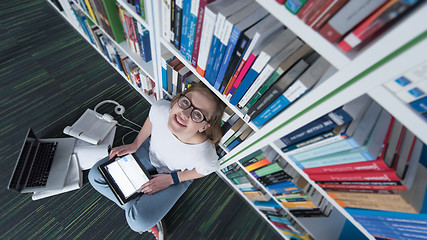 Image showing female student study in library, using tablet and searching for 