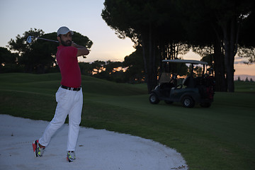 Image showing golfer hitting a sand bunker shot on sunset