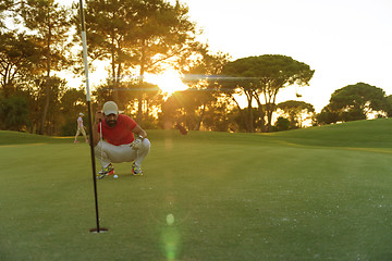 Image showing golf player aiming perfect  shot on beautiful sunset