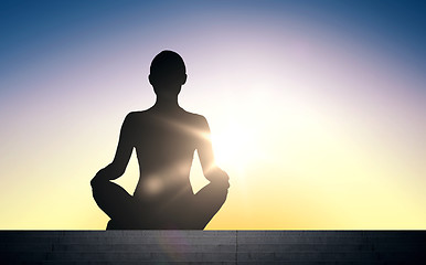 Image showing woman meditating in yoga lotus pose over sun light