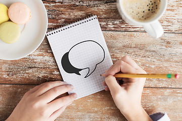 Image showing close up of hands drawing text bubble in notebook