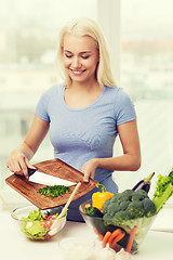 Image showing smiling woman cooking vegetable salad at home