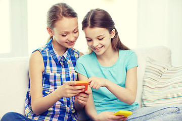 Image showing happy girls with smartphones sitting on sofa