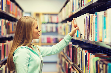 Image showing happy student girl or woman with book in library