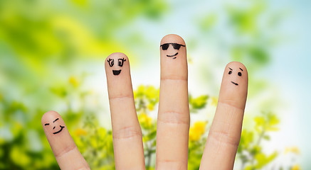 Image showing close up of fingers with smiley faces over nature