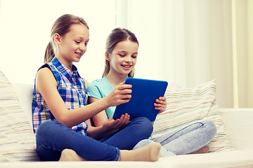 Image showing happy girls with tablet pc sitting on sofa at home