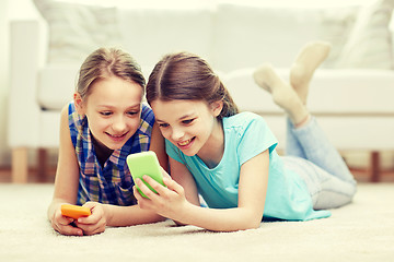 Image showing happy girls with smartphones lying on floor