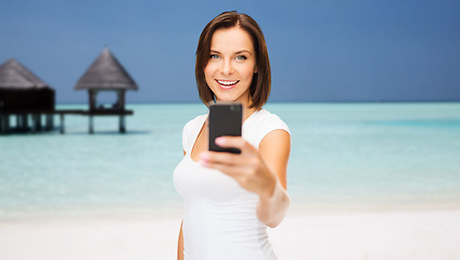 Image showing happy woman taking picture by smartphone on beach