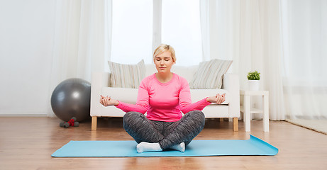 Image showing happy woman stretching leg on mat at home