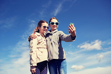 Image showing happy girls with smartphone taking selfie outdoors