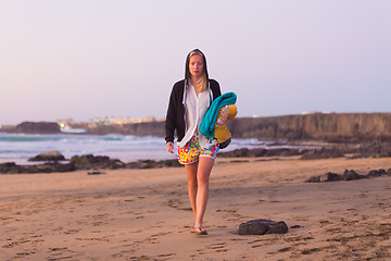 Image showing Sporty woman walking on sandy beach in sunset.