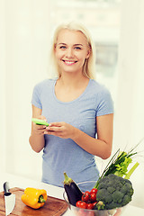 Image showing smiling woman with smartphone cooking vegetables