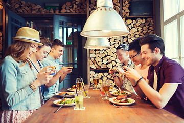 Image showing happy friends with smartphones picturing food