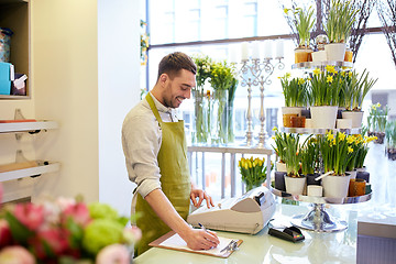 Image showing florist man with clipboard at flower shop counter
