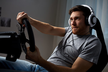 Image showing man playing car racing video game at home