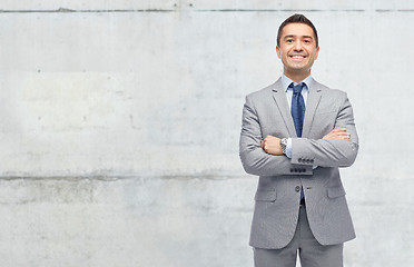 Image showing happy businessman in suit over concrete wall