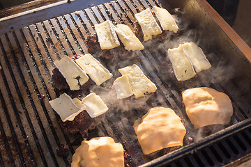 Image showing Beef burgers being grilled on barbecue.