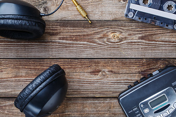 Image showing Cassette tapes, cassette player and headphones over wooden table. top view.