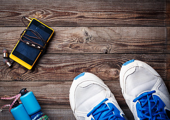 Image showing Sports equipment - sneakers, skipping rope, smartphone and headphones. Sport background on wooden floor, top view.